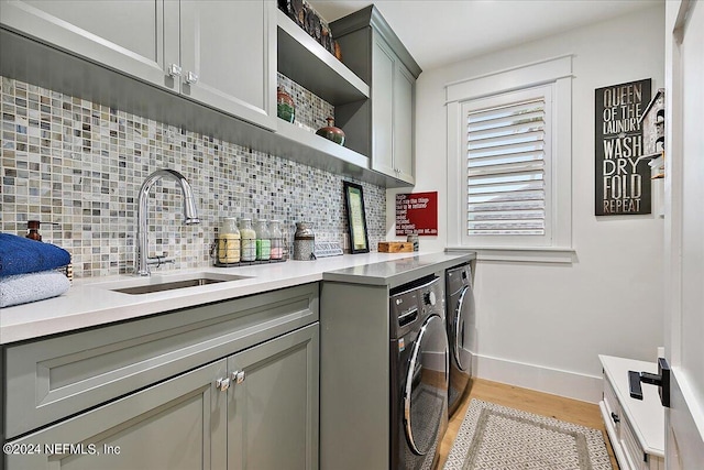 washroom with cabinets, sink, independent washer and dryer, and light hardwood / wood-style floors