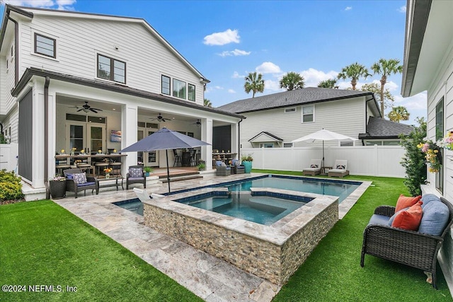 rear view of house with a swimming pool with hot tub, a lawn, a patio, and ceiling fan