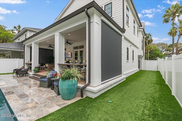 view of side of property with a lawn, a patio, and ceiling fan