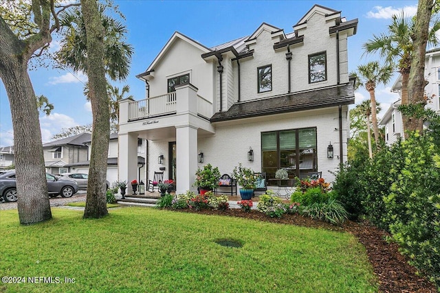 view of front of house featuring a balcony and a front lawn