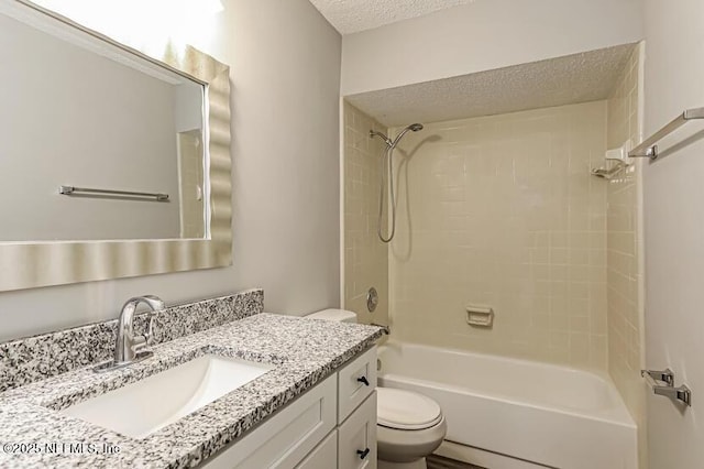 full bathroom featuring vanity, tiled shower / bath, toilet, and a textured ceiling