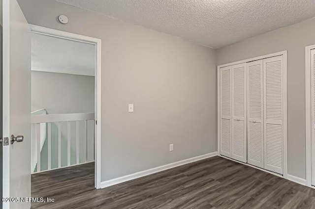 unfurnished bedroom featuring dark wood-type flooring, a closet, and a textured ceiling