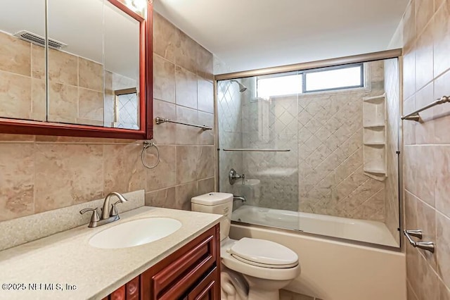 full bathroom featuring tile walls, vanity, bath / shower combo with glass door, and toilet