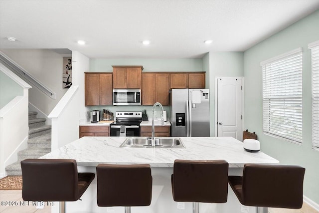 kitchen featuring a kitchen island with sink, stainless steel appliances, a breakfast bar, and sink