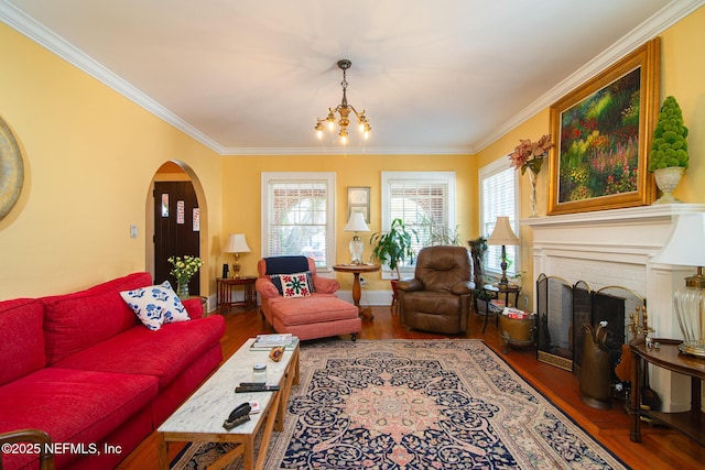 living room featuring hardwood / wood-style flooring, ornamental molding, an inviting chandelier, and a fireplace