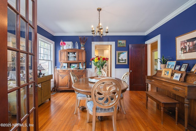 dining room with crown molding, a notable chandelier, and light wood-type flooring