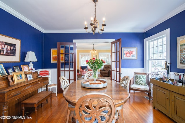 dining room with ornamental molding, light wood-type flooring, a wealth of natural light, and a chandelier