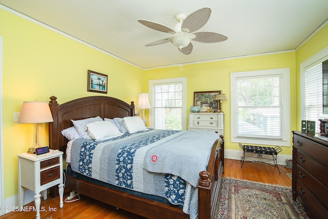 bedroom with crown molding, dark hardwood / wood-style floors, and ceiling fan