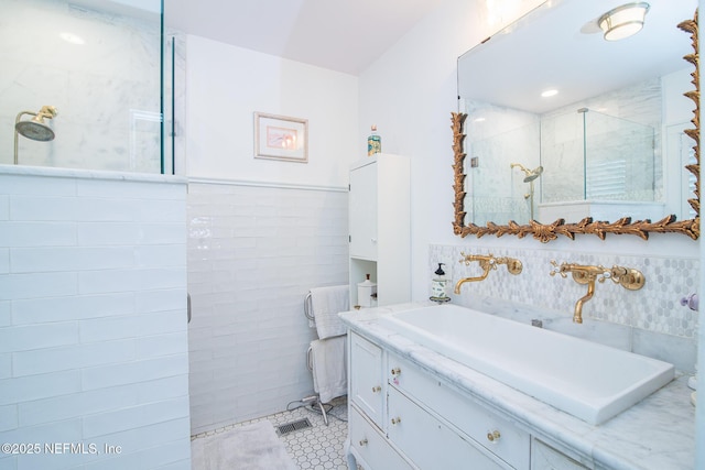 bathroom with vanity, tile walls, and tiled shower