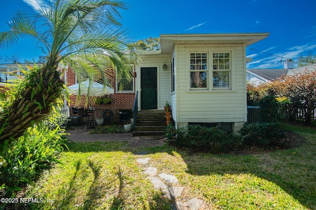 bungalow with a front lawn and central air condition unit