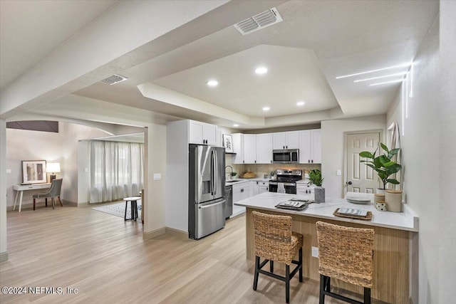 kitchen featuring a tray ceiling, white cabinetry, sink, kitchen peninsula, and stainless steel appliances