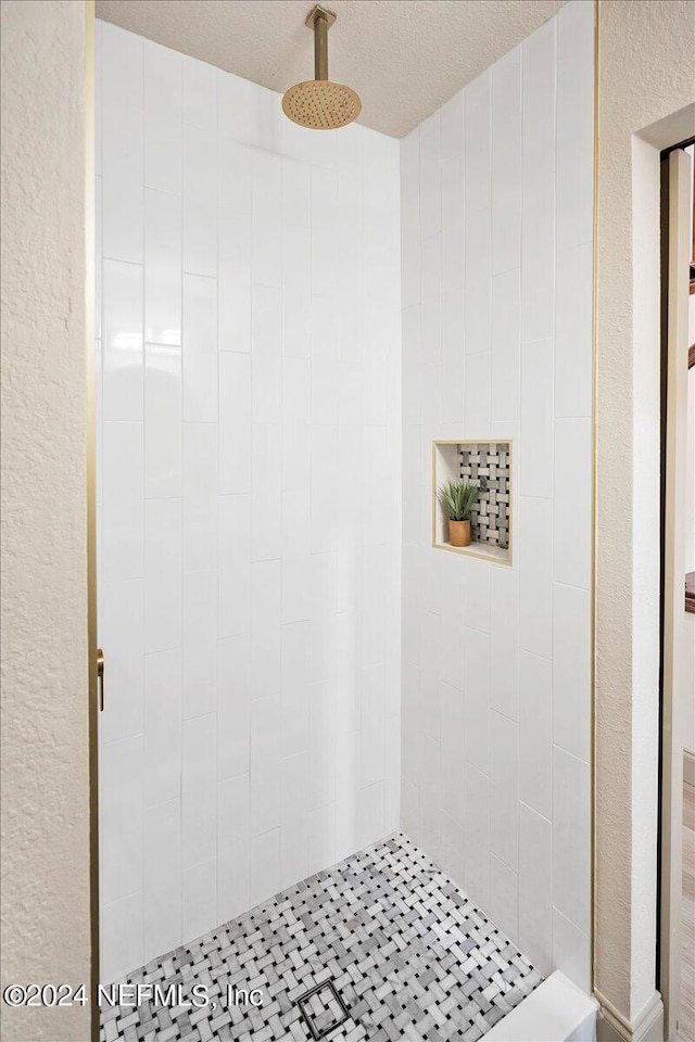 bathroom with a textured ceiling and tiled shower