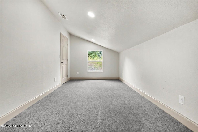 bonus room featuring light colored carpet, lofted ceiling, and a textured ceiling