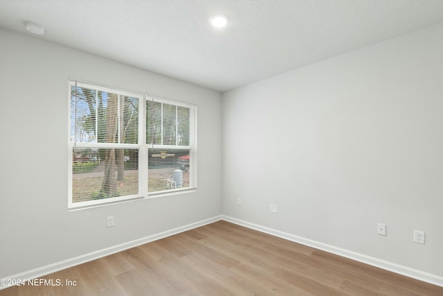 unfurnished room with light hardwood / wood-style floors and a textured ceiling