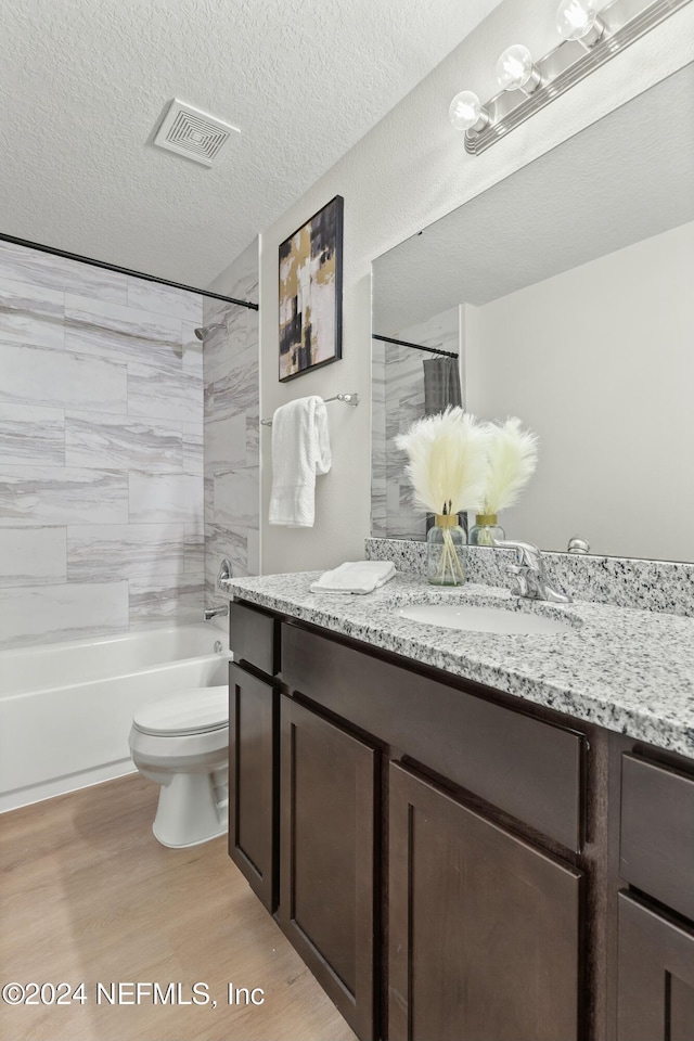 full bathroom featuring toilet, tiled shower / bath, a textured ceiling, vanity, and hardwood / wood-style flooring