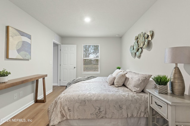 bedroom with light hardwood / wood-style flooring and a textured ceiling