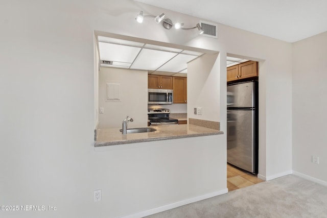 kitchen featuring sink, light colored carpet, light stone counters, kitchen peninsula, and stainless steel appliances