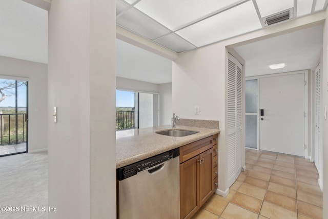 kitchen with light tile patterned flooring, stainless steel dishwasher, and sink