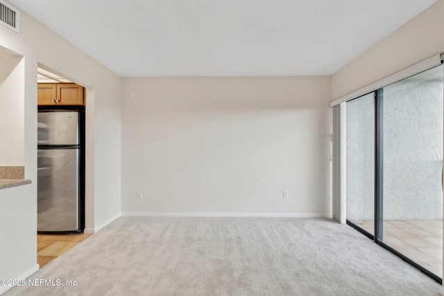 unfurnished bedroom featuring light carpet and stainless steel fridge