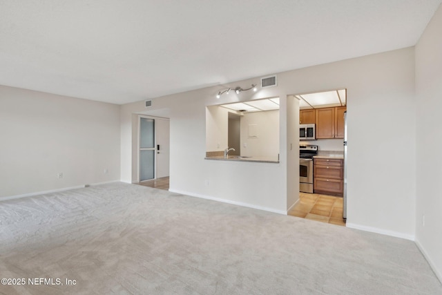 unfurnished living room with sink and light carpet