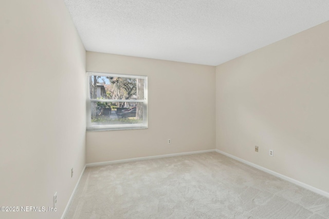 spare room featuring light colored carpet and a textured ceiling