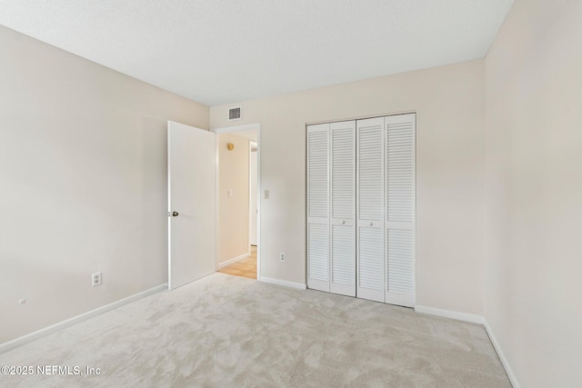 unfurnished bedroom with light carpet and a closet