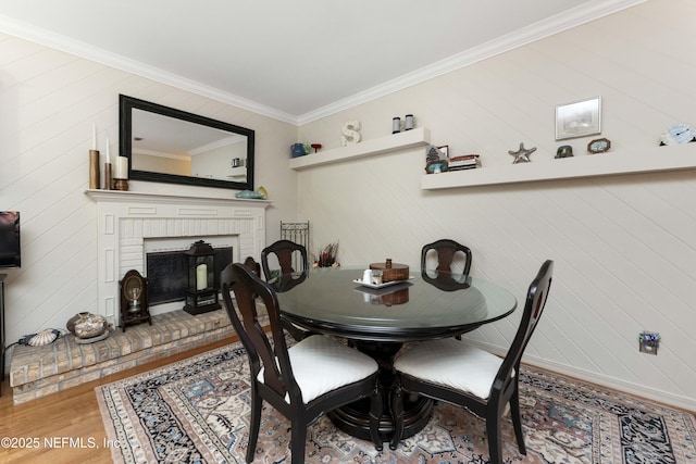 dining space featuring ornamental molding, wood-type flooring, and a fireplace