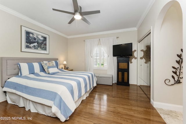 bedroom with hardwood / wood-style flooring, ceiling fan, crown molding, and a closet