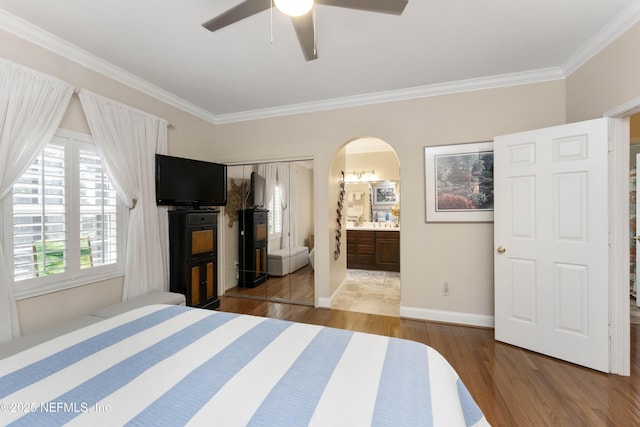 bedroom with crown molding, ceiling fan, connected bathroom, and hardwood / wood-style floors