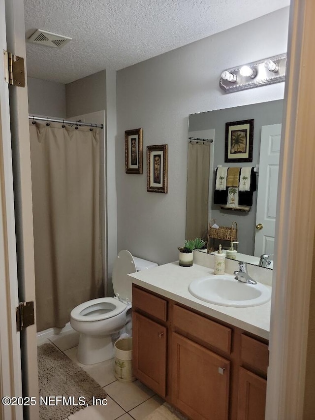 bathroom featuring vanity, tile patterned flooring, toilet, and a textured ceiling