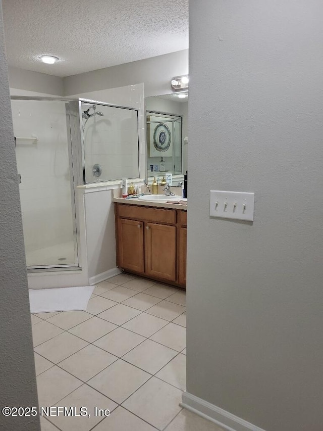 bathroom with tile patterned flooring, vanity, an enclosed shower, and a textured ceiling