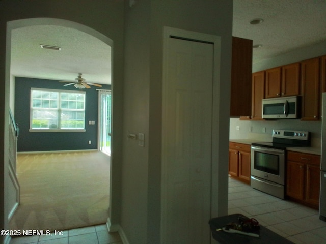 kitchen with stainless steel appliances, light tile patterned flooring, ceiling fan, and a textured ceiling