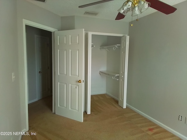 unfurnished bedroom with ceiling fan, a closet, light carpet, and a textured ceiling