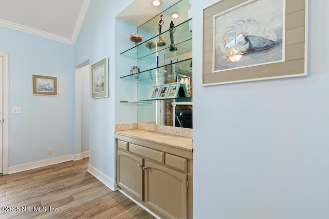 bar featuring crown molding, light brown cabinetry, and light hardwood / wood-style floors