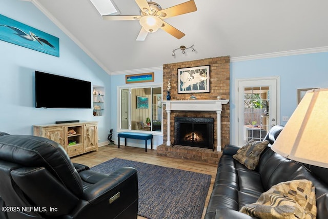 living room with a brick fireplace, crown molding, vaulted ceiling, and light hardwood / wood-style floors