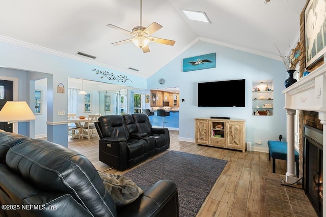 living room featuring wood-type flooring, ornamental molding, ceiling fan, and a fireplace