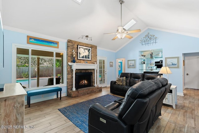 living room featuring vaulted ceiling, ornamental molding, ceiling fan, light hardwood / wood-style floors, and a brick fireplace