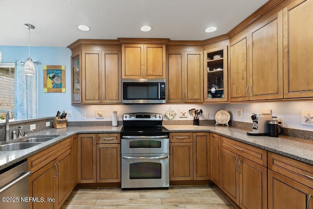 kitchen with sink, hanging light fixtures, dark stone counters, light wood-type flooring, and stainless steel appliances