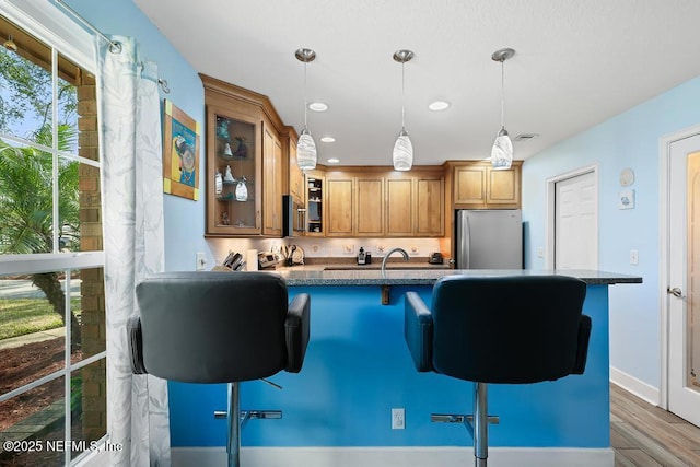 kitchen featuring decorative light fixtures, stainless steel fridge, a breakfast bar area, and kitchen peninsula