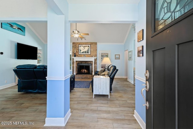 entryway with lofted ceiling, a fireplace, ceiling fan, and light wood-type flooring