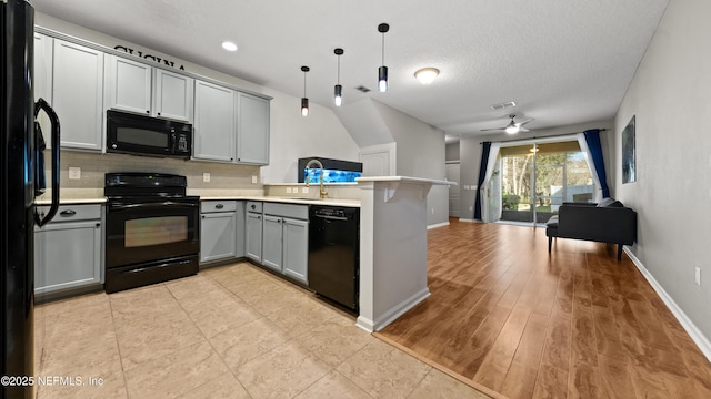 kitchen with sink, gray cabinets, kitchen peninsula, pendant lighting, and black appliances