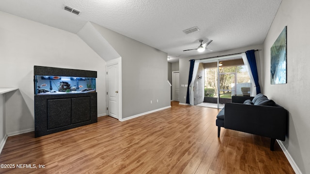 living room with hardwood / wood-style flooring, ceiling fan, and a textured ceiling