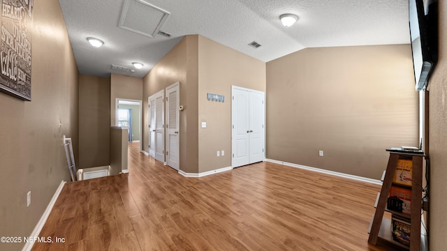 interior space with hardwood / wood-style floors, vaulted ceiling, two closets, and a textured ceiling