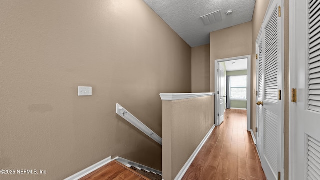 corridor featuring a textured ceiling and light wood-type flooring