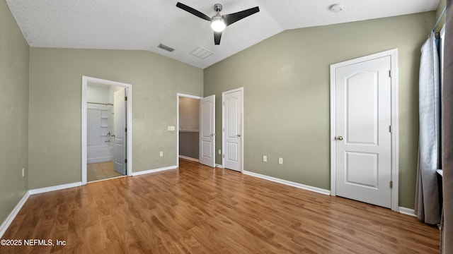 unfurnished bedroom with vaulted ceiling, ensuite bath, and light hardwood / wood-style flooring