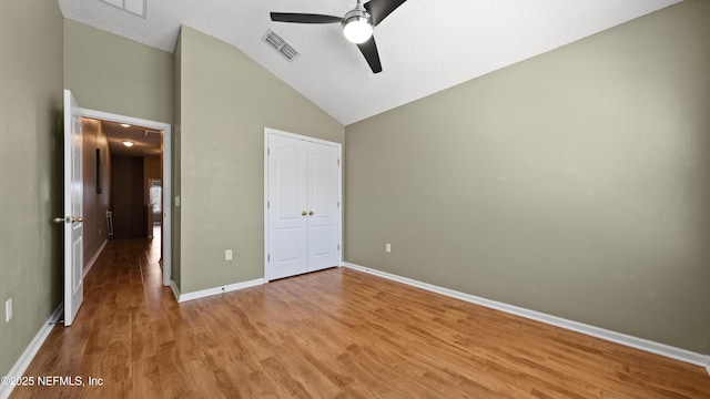 unfurnished bedroom featuring vaulted ceiling, hardwood / wood-style flooring, ceiling fan, a textured ceiling, and a closet