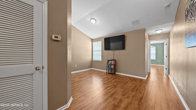 hallway featuring a wealth of natural light, light hardwood / wood-style floors, and a textured ceiling