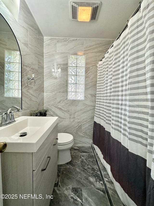 bathroom with vanity, a wealth of natural light, tile walls, and toilet