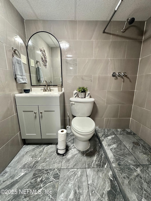 bathroom featuring vanity, toilet, tile walls, and walk in shower