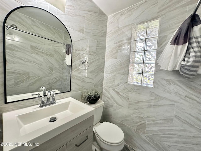 bathroom featuring vanity, tile walls, and toilet